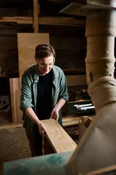 A dedicated female carpenter works carefully with wood, demonstrating her craftsmanship in a lively workshop. — Stock Photo