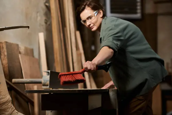 In a well-equipped workshop, a dedicated female carpenter skillfully crafts wood while focused on her project. — Stock Photo