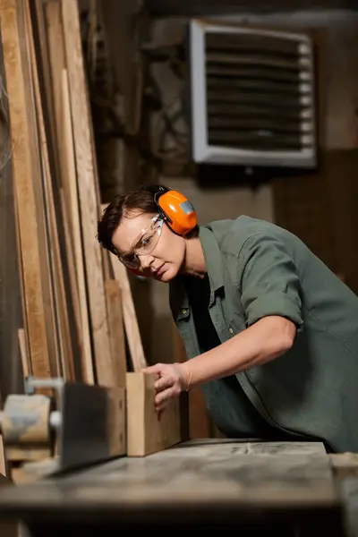 A skilled female carpenter focuses intently as she crafts wood in her workshop, showcasing her craftsmanship. — Stock Photo