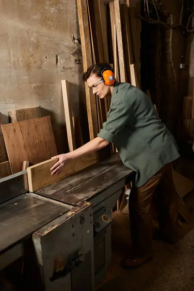 A skilled female carpenter carefully works on wood, showcasing craftsmanship in her workshop filled with materials. — Stock Photo