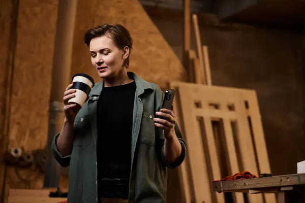 In a lively workshop, a skilled female carpenter sips coffee and checks her tools, embracing her craft. — Stock Photo