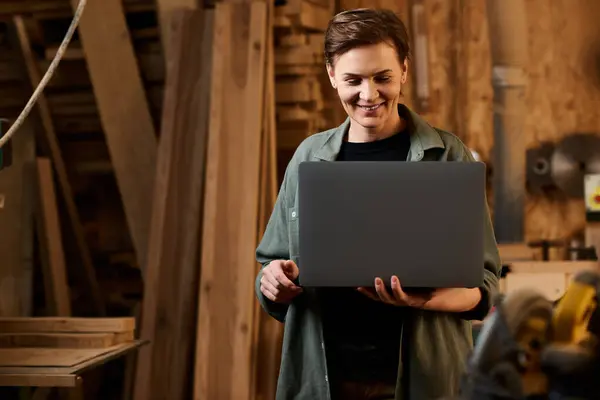 A skilled female carpenter explores design ideas on a laptop amid her woodworking workshop, showcasing her talent. — Stock Photo