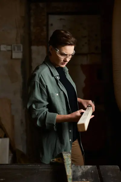 A dedicated female carpenter focuses on shaping a piece of wood in a vibrant workshop filled with tools. — Stock Photo