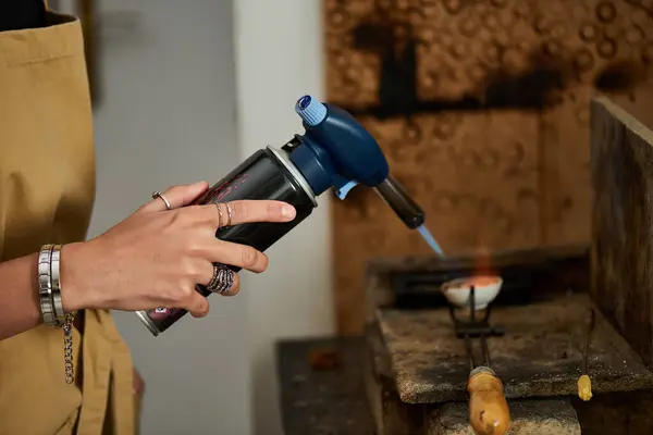 An artisan focuses intently while using a torch to shape exquisite jewelry in her studio. — Stock Photo