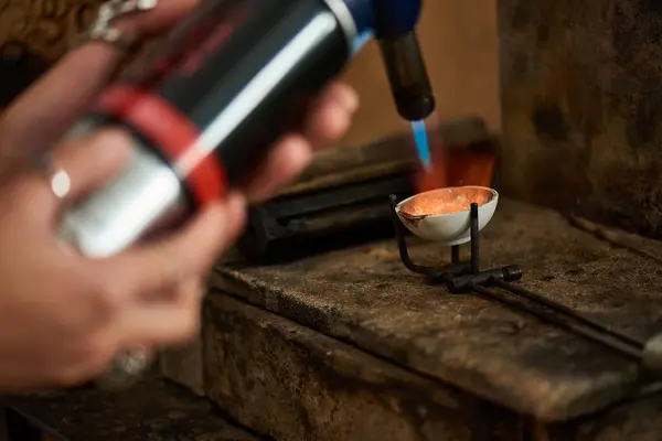 A skilled artisan uses a blowtorch to melt metal, creating exquisite jewels in a cozy workshop. — Stock Photo