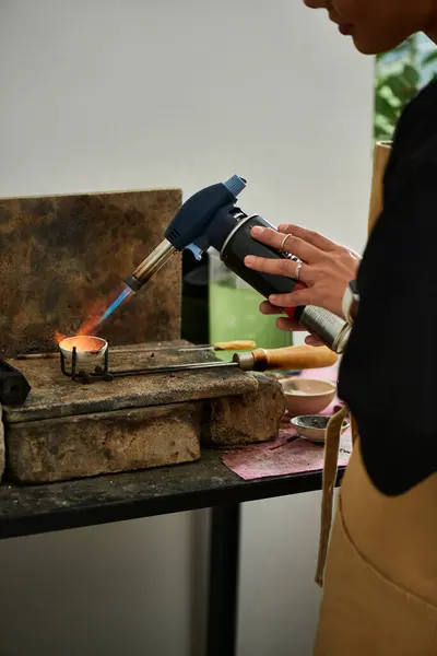 Un individuo talentoso utiliza cuidadosamente una antorcha para crear impresionantes joyas en un banco de trabajo vintage. - foto de stock
