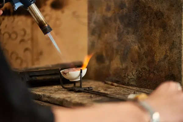 A skilled craftsman uses a torch to create stunning jewelry in an artisan workshop. — Stock Photo