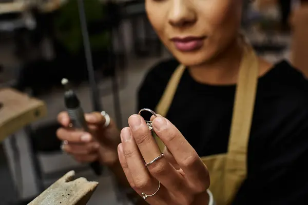 A skilled artisan carefully holds a precious jewel while working on her craft. — Stock Photo