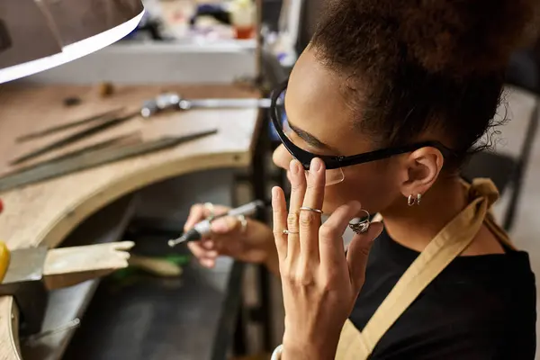 Un designer talentueux se concentre intensément sur la création d'ornements exquis tout en étant entouré d'outils. — Photo de stock