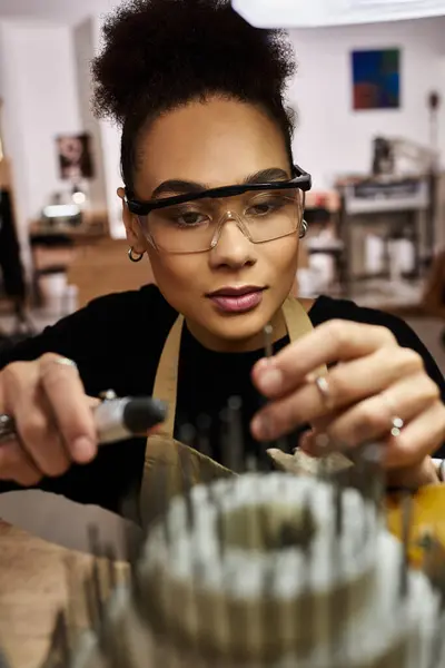 An artisan focuses intently while crafting beautiful jewels in a lively creative studio. — Stock Photo