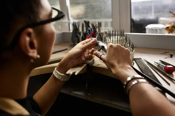 A skilled artisan crafts intricate jewelry in a bright, detail focused workspace. — Stock Photo