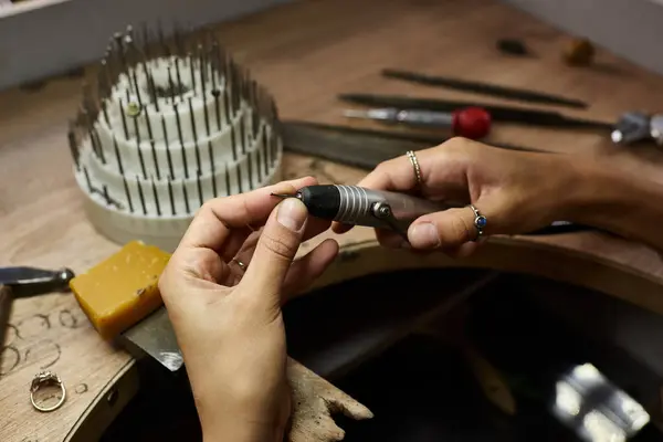 A woman meticulously shapes a beautiful jewel while surrounded by tools and materials. — Stock Photo