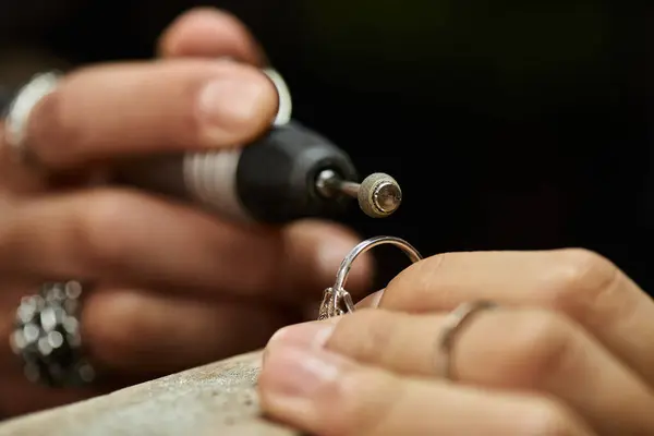 Un artesano experto está pulido cuidadosamente un anillo impresionante con joyas brillantes. - foto de stock
