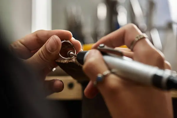 Skilled artisan focuses on adding delicate details to a beautiful piece of jewelry in a workshop. — Stock Photo