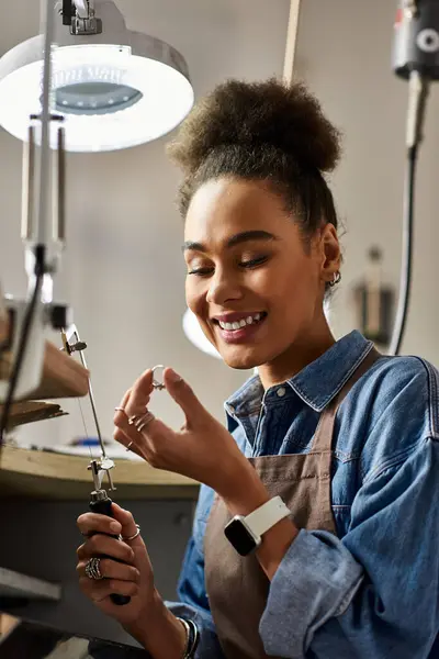 A joyful artisan creates exquisite jewelry in a bright, lively workspace. — Stock Photo