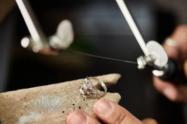 A skilled artisan works meticulously with a delicate silver ring, showcasing craftsmanship. — Photo de stock