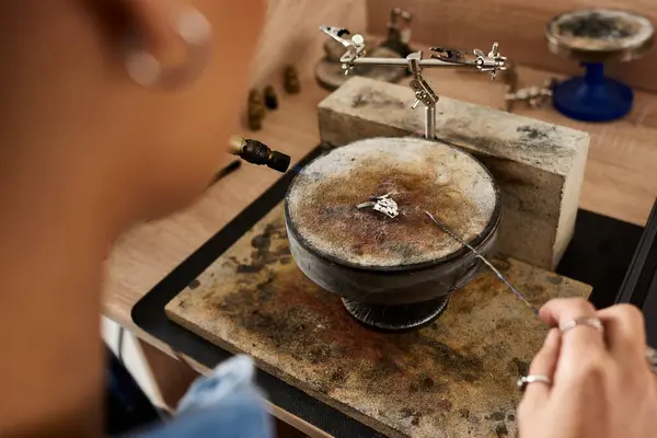 A talented woman delicately crafts intricate jewelry in her creative workspace filled with tools. — Stock Photo