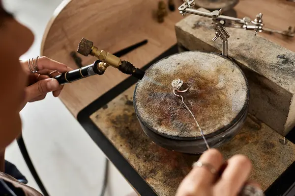 An artisan expertly uses tools to create stunning jewelry pieces amidst a warm, inviting workshop. — Stock Photo