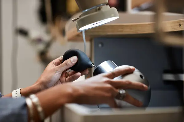 Un artigiano si concentra intensamente sulla lavorazione di gioielli squisiti utilizzando strumenti di precisione in un accogliente laboratorio. — Foto stock