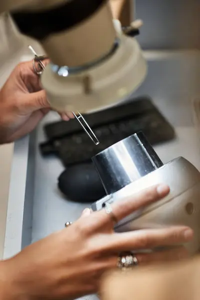 An artisan carefully inspects beautiful jewels using specialized tools in a well lit workspace. — Stock Photo