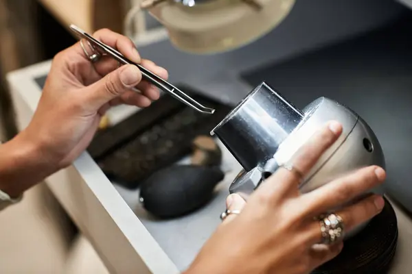 An artisan focuses intently on examining a gleaming silver piece using specialized tools. — Stock Photo
