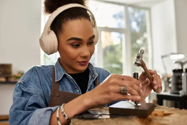 A talented woman delicately works on creating exquisite jewelry while wearing headphones. — Stock Photo