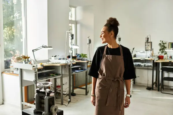 A skilled woman smiles while working in a sunlit studio adorned with artistic tools and treasures. — Stock Photo