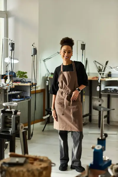 A talented woman stands confidently in her workshop, surrounded by tools, creating stunning jewelry. — Stock Photo