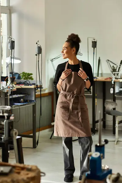 The skilled artisan stands proudly among her intricate jewelry designs, focusing on her craft. — Stock Photo