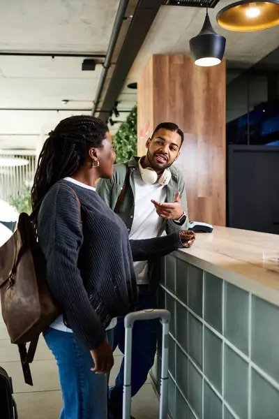 Una coppia condivide un momento gioioso presso la hall dell'hotel, desiderosi di check-in per la loro avventura di vacanza. — Foto stock