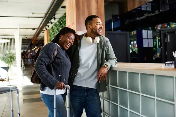 Una feliz pareja se relaja en un animado vestíbulo del hotel, emocionados por sus aventuras de vacaciones por delante. - foto de stock