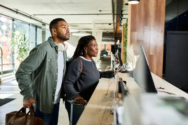 A couple stands together at the hotel reception, anticipatory smiles reflecting their vacation excitement. — Stock Photo