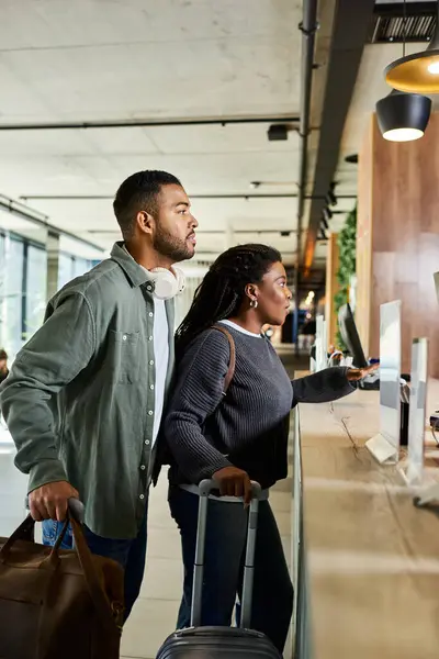 A young African American couple eagerly checks in at a hotel lobby, ready to begin their vacation adventure. — Stock Photo