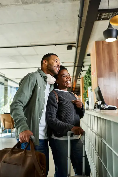 A cheerful young African American couple arrives at a modern hotel lobby, ready to start their vacation. — Stock Photo