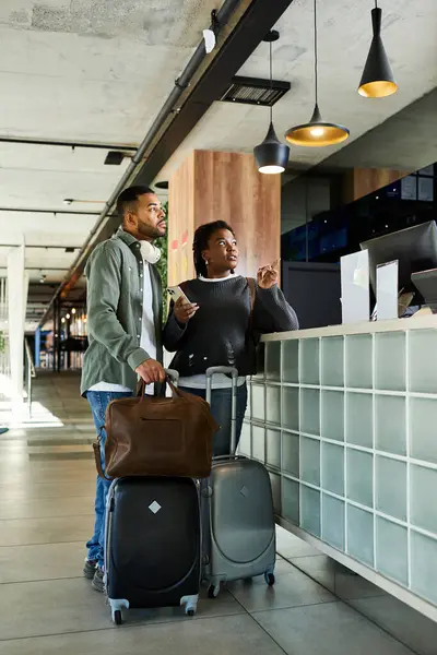 Ein junges Paar steht an der Hotelrezeption, bereit für den aufregenden Urlaub mit Gepäck in der Hand. — Stockfoto
