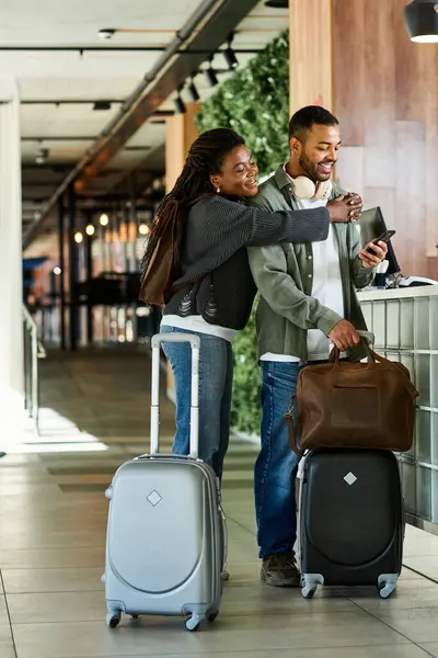 Ein fröhliches junges Paar kommt in ihrem Hotel an und lächelt beim Einchecken mit dem Gepäck im Schlepptau. — Stockfoto