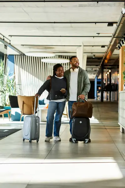 A young African American couple smiles widely as they walk through a chic hotel lobby, ready for adventure. — Stock Photo