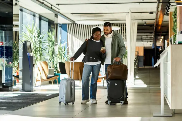 A young couple joyfully arrives at a modern hotel lobby, eager to start their vacation filled with adventure. — Stock Photo