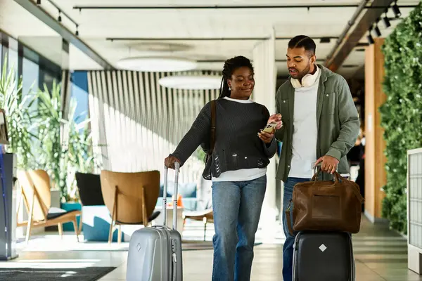 A young couple explores a stylish hotel lobby, excited for their vacation adventures ahead. — Stock Photo