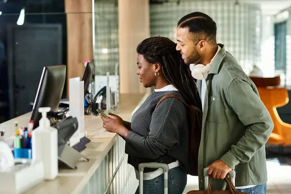 Una giovane coppia afroamericana fa il check-in al loro hotel, piena di eccitazione per la loro vacanza insieme. — Foto stock