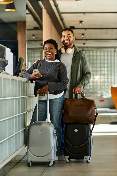 Ein fröhliches junges Paar steht in der Hotellobby und freut sich darauf, gemeinsam in den Urlaub zu starten.. — Stockfoto
