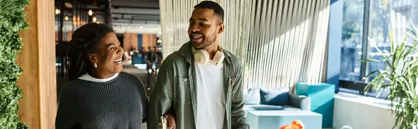 A young African American couple shares laughter and smiles while exploring a stylish hotel lobby setting. — Stock Photo