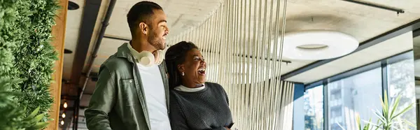 A cheerful young couple laughs together while exploring a stylish hotel lobby during their vacation. — Stock Photo