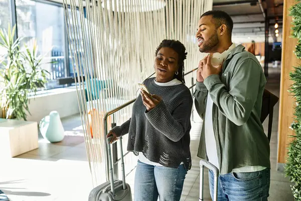A cheerful couple checks in at a stylish hotel, ready to start their adventure on vacation together. — Stock Photo