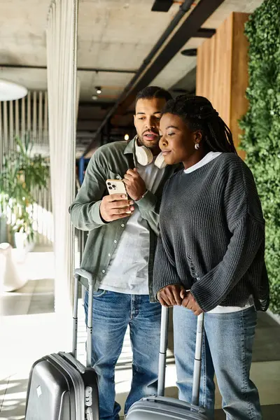 A young couple excitedly discusses their travel plans while waiting in a modern hotel lobby. — Stock Photo