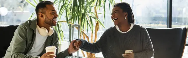 A young African American couple is sharing joyful moments in a vibrant hotel lobby while on vacation. — Stock Photo