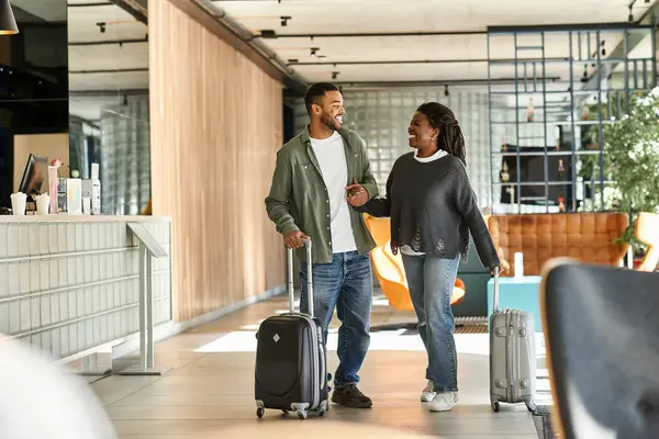 A joyful young couple strolls through a stylish hotel lobby, excited for their vacation ahead. — Stock Photo