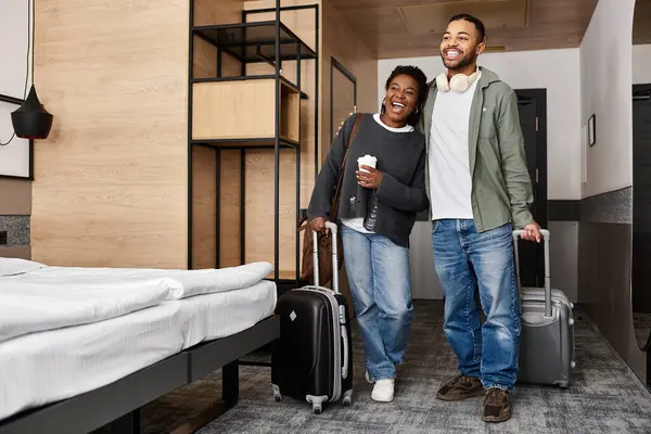 A young couple embraces happiness while unpacking their bags in a stylish hotel room during their vacation. — Stock Photo