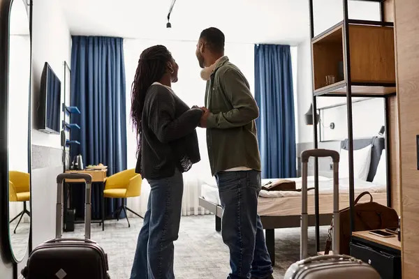 Um jovem casal afro-americano abraça-se em seu quarto de hotel, desfrutando de umas férias românticas. — Fotografia de Stock