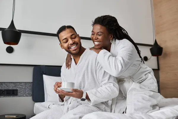 A loving couple shares a warm moment, sipping coffee and smiling in their hotel suite while on vacation. — Stock Photo